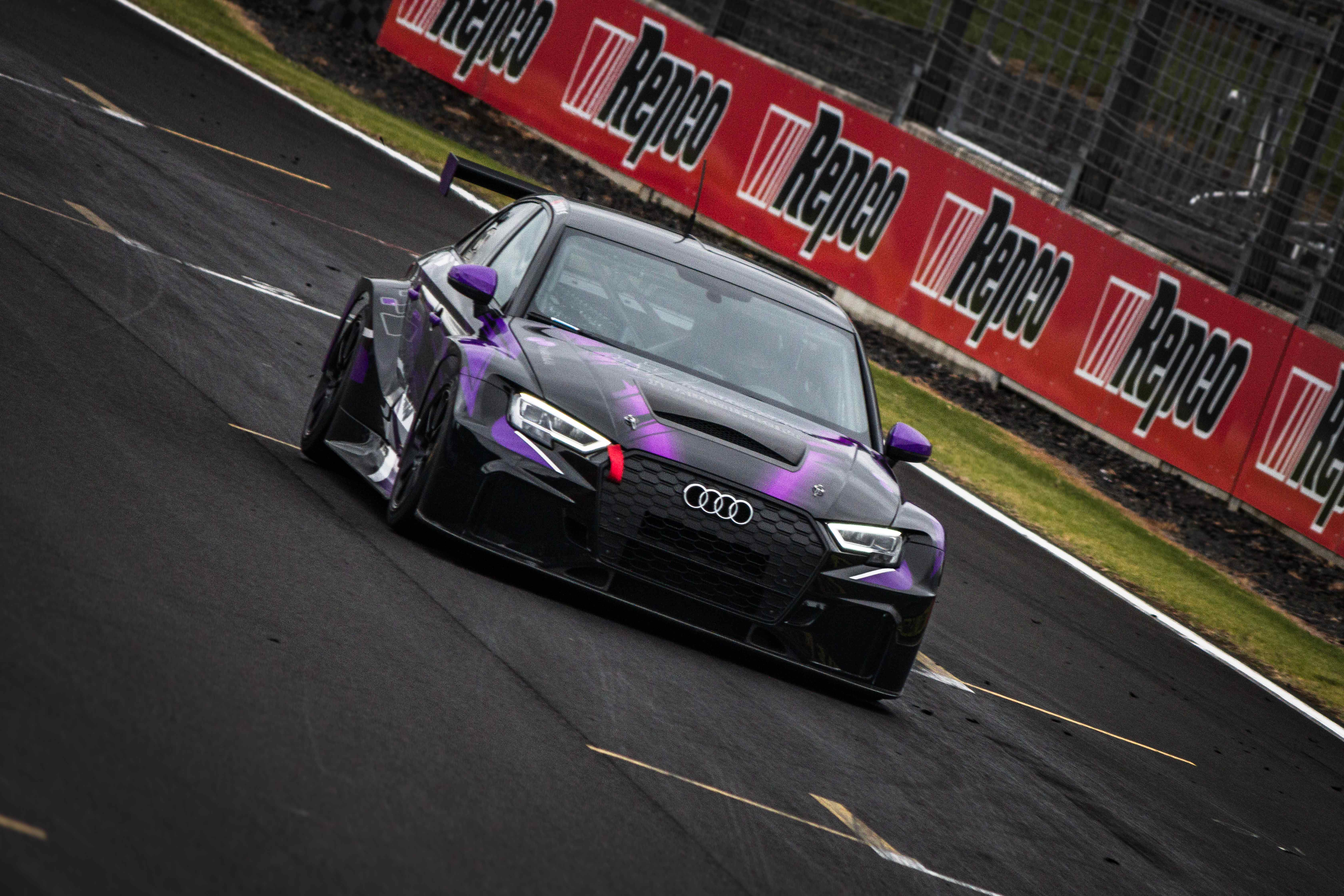 Race cars lined up beside circuit barriers